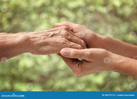 Una badante che tiene la mano a un anziano