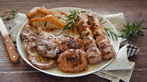 Piatto di lonza di maiale con un contorno misto di verdure grigliate e patate al forno