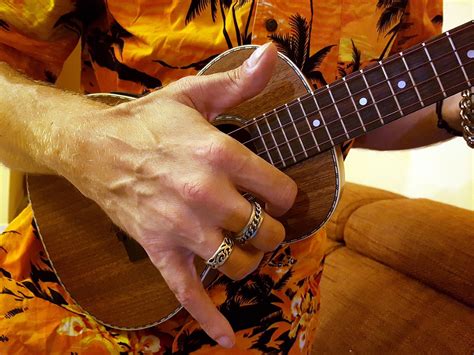 Mano destra che esegue lo strumming su una chitarra acustica