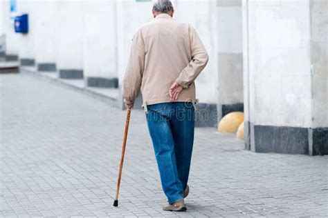 Anziano che cammina all'aperto con un bastone
