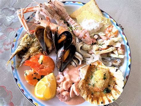 Varietà di antipasti di pesce con calici di vino bianco