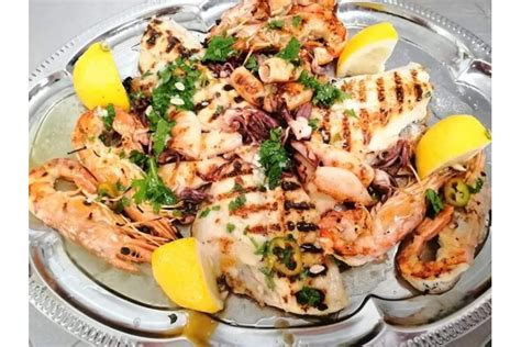 Grigliata mista di pesce con bottiglie di vino bianco e rosé