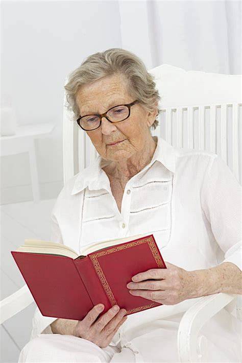 Donna anziana sorridente che legge un libro