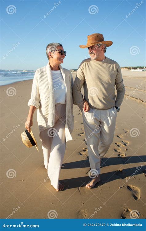 Coppia anziana che passeggia mano nella mano su una spiaggia