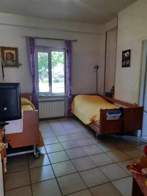 Interno di una stanza di casa di riposo accogliente con letto, comodino e finestra